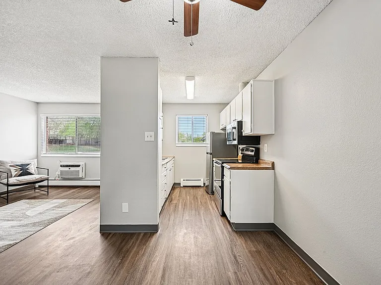Modern kitchen with stainless steel appliances, bright living area, and elegant wood flooring