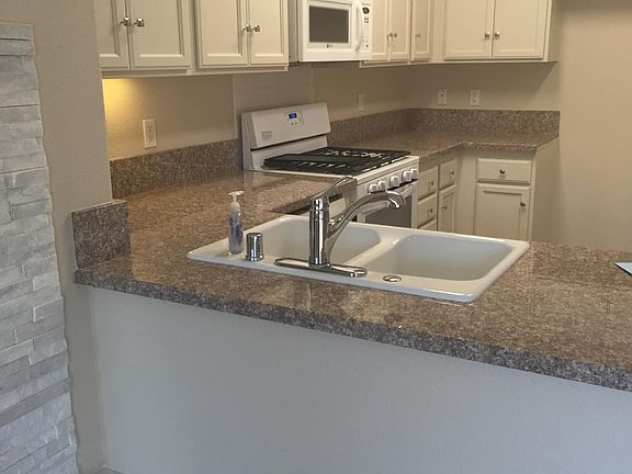 VIEW OF KITCHEN WITH GRANITE COUNTERS, MICROWAVE FROM LIVING