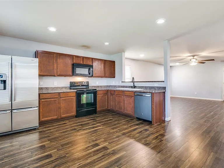 Kitchen with ceiling fan, sink, dark hardwood / wood-style flooring, and black appliances