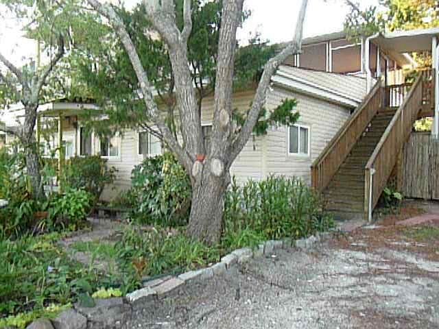Front of house with staircase on side going to 2nd floor entrance, adjacent to parking area. Wide stairs, motion light,