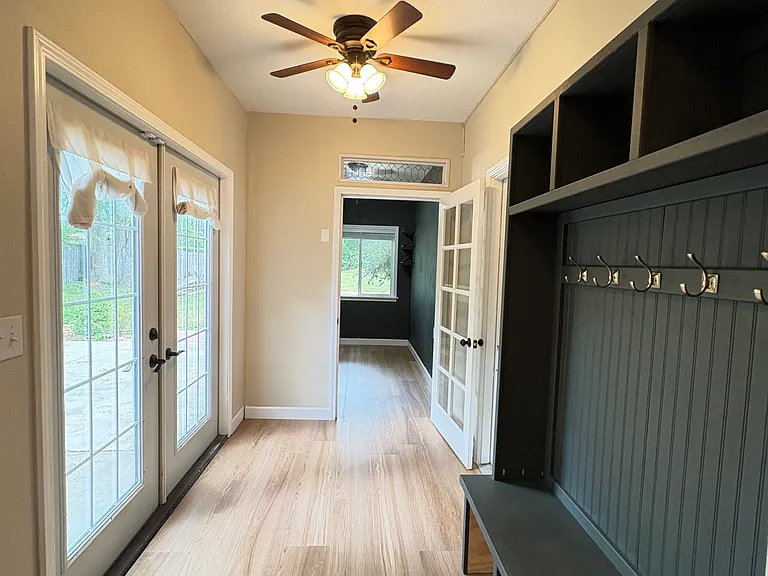 Step inside from the back patio through elegant French doors to a welcoming entry space featuring a convenient coat and shoe rack, which can also be accessed through the garage and side porch.