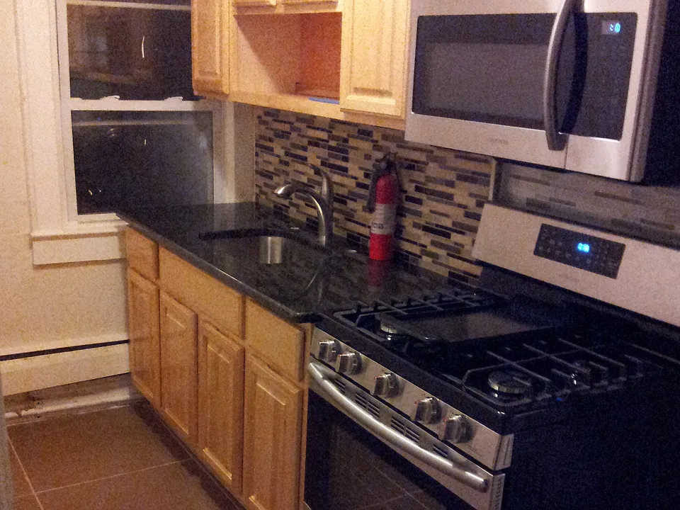 Kitchen features tiled back splash, granite counter top and
