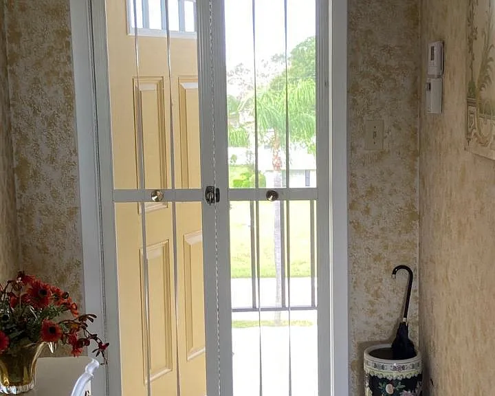 exterior front entrance door opens out onto exterior walkway with interior screen door in use.