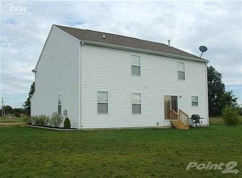 Back of home with landscaping and storage shed.
