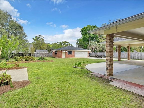 View of yard featuring driveway, a garage, an outbuilding, and a patio area