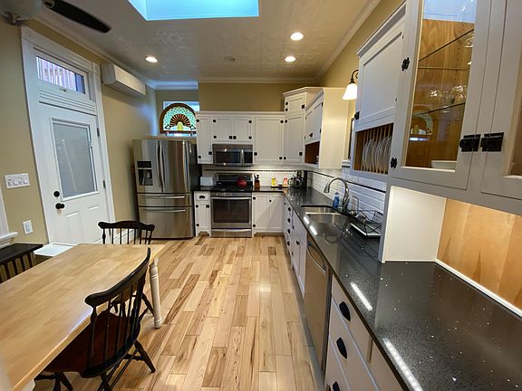 Kitchen and view of door to back patio and grill Kitchen includes Refrigerator, Gas stove, Built in Microwave, water filter, coffee maker, dishes, flatware, glasses, and pots and pans.
