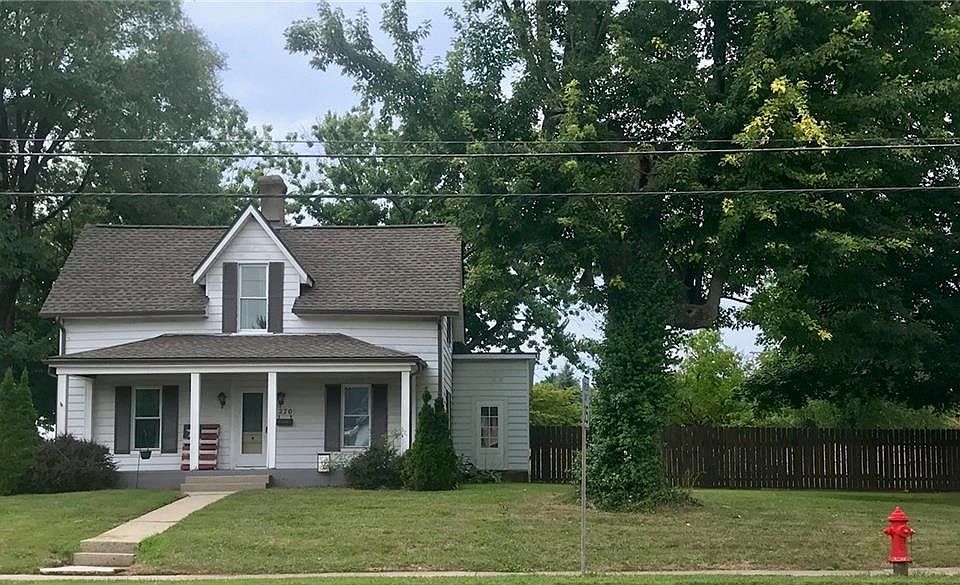Front porch and fenced-in yard and mature trees.