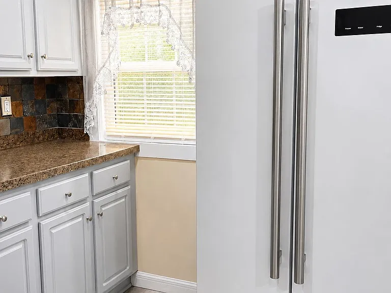 Efficient kitchen with ample cabinet storage, durable countertops, and a full-size side-by-side refrigerator.