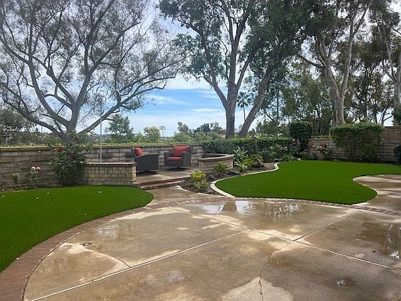 Large cement patio areas with brick borders. Lush backyard planter areas with fruit trees. Easy care artificial turf.