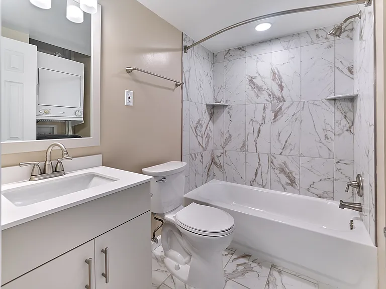 Updated bathroom with marble-style tile surround, modern fixtures, and sleek vanity in this 2 Bed,1 Bath, 908 sq. ft. home.