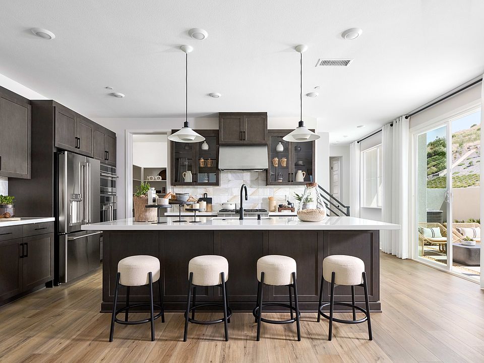 A modern and sleek kitchen with dark cabinets, a large island with bar stools, and a bright and airy