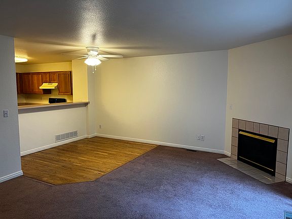 Front room with gas fireplace and natural wood floor in dining area