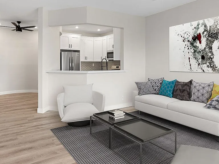 Hardwood floored living room with view of kitchen and dining area.