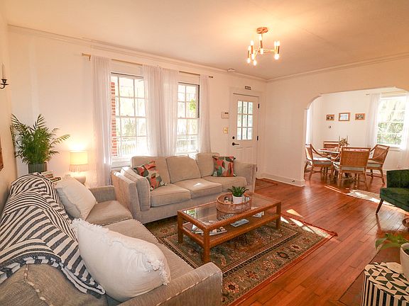 Main living room features two large comfortable couches, 50 inch smart tv, original hardwood floors and access to front porch