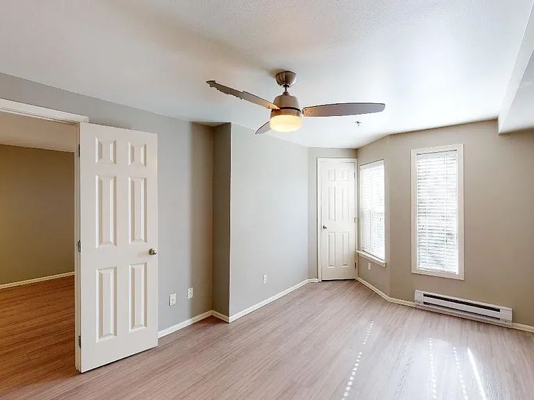Spacious apartment bedroom with wood-style flooring.
