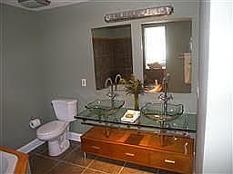 Glass top double vanity with two glass bowl sinks, dec fixtures, and tile flrs