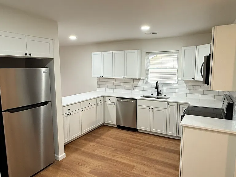 Modern open-concept kitchen featuring generous countertop space, abundant white cabinetry, subway-tile backsplash, stainless-steel appliances, built-in microwave, and a large peninsula perfect for dining or entertaining.