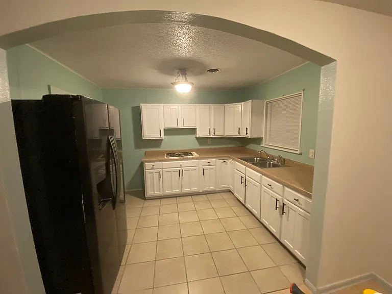 Kitchen view from dining room. Refrigerator that is provided is white (not black) and is top freezer style.