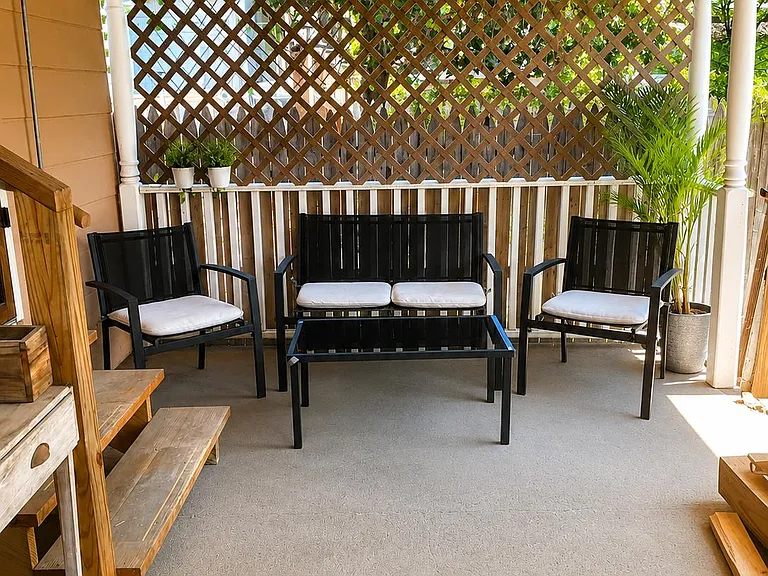 Covered porch seating area with cushioned lounge set, privacy lattice, and space for relaxing or hosting outdoors.
