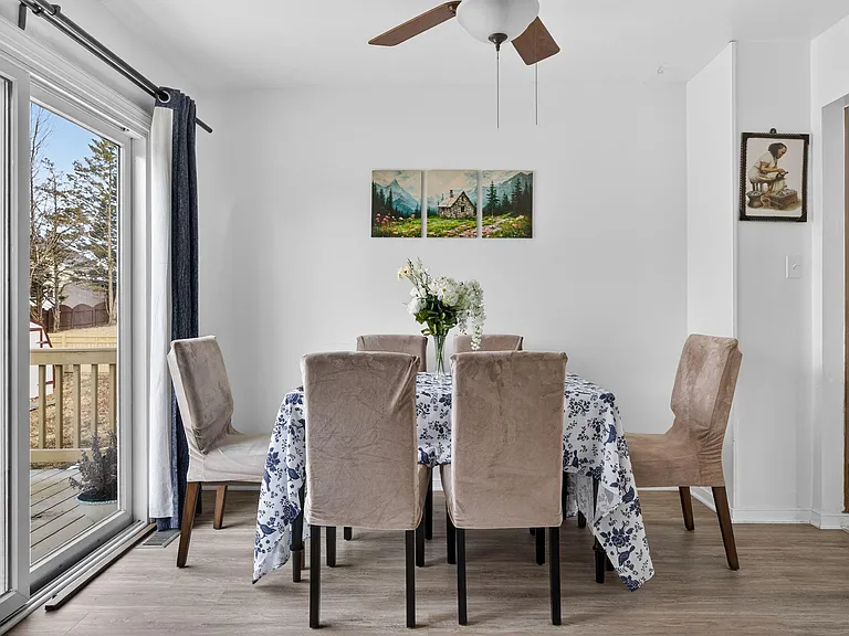Dining area with a 4-seat table, ceiling fan, and large sliding glass door providing easy access to the deck.