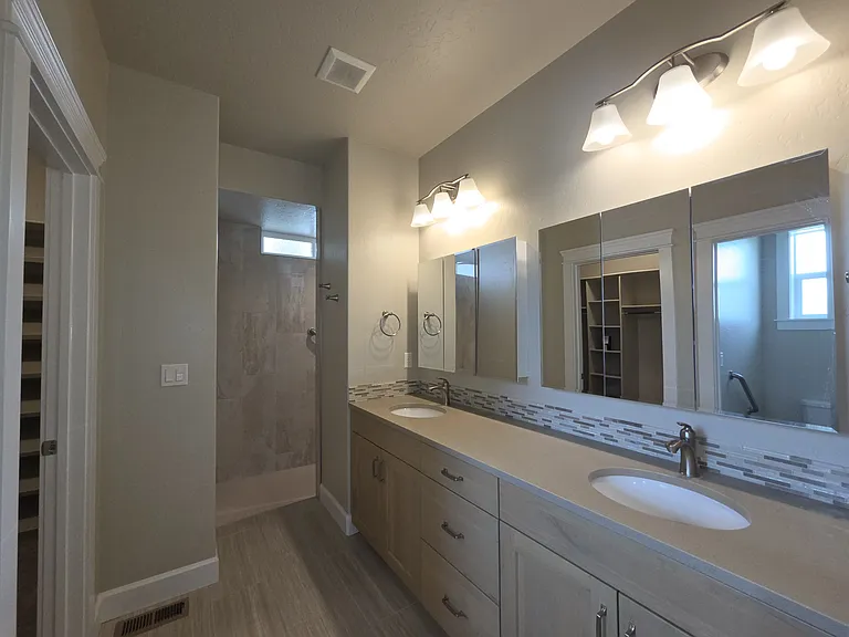 MASTER BATHROOM WITH DOUBLE SINKS AND MIRRORED VANITIES.