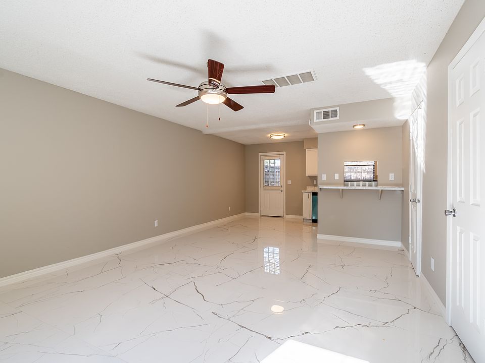 Bright and inviting with large windows that bring in natural light. Features neutral tones, ceiling fan, and an open layout that flows seamlessly into the dining area_ideal for entertaining or relaxing.