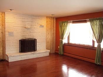 The living room has beautiful wood flooring and a fireplace.