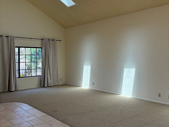 View of livingroom with skylights and front window. New carpeting and drapes.