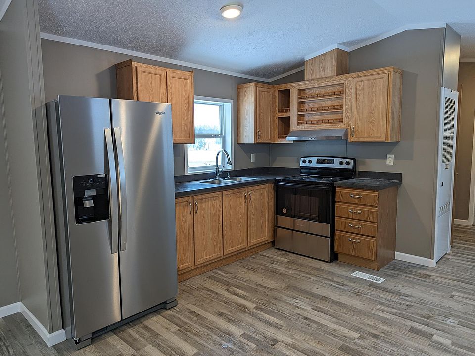 Kitchen w stainless appliances, window above sink and spice rack above stove