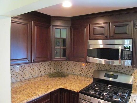 Newly remodeled kitchen with granite countertops, backsplash, GE profile microwave and stove w/gas cooktop