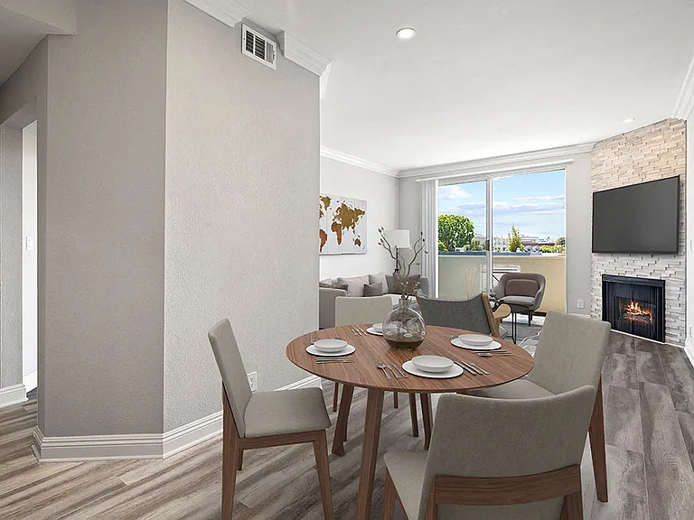 Hardwood floored dining room with view of balcony and stone walled fireplace.