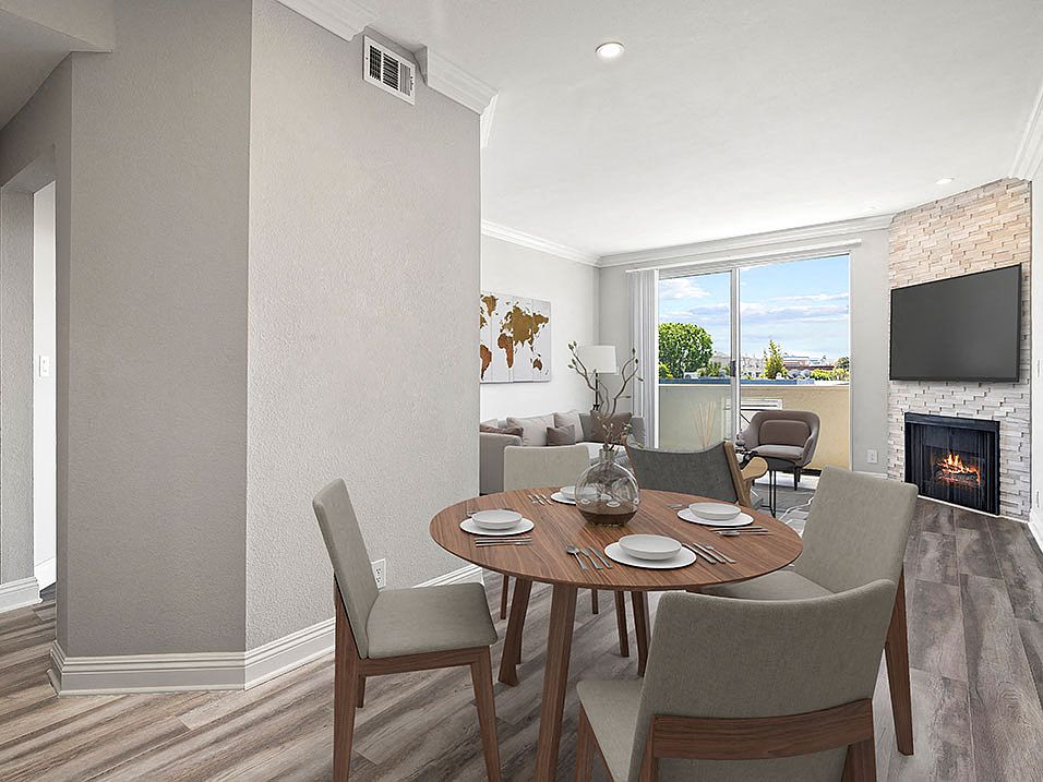 Hardwood floored dining room with view of balcony and stone walled fireplace.