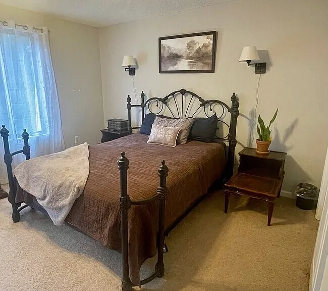 Primary bedroom with carpeted flooring, window, and closet space.