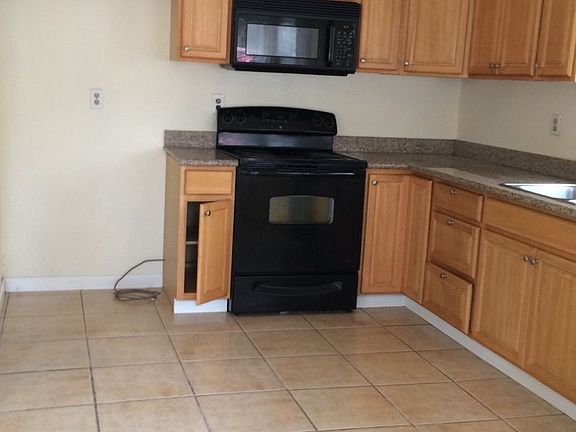 Kitchen with oak wood cabinets, tile floor, and granite coun