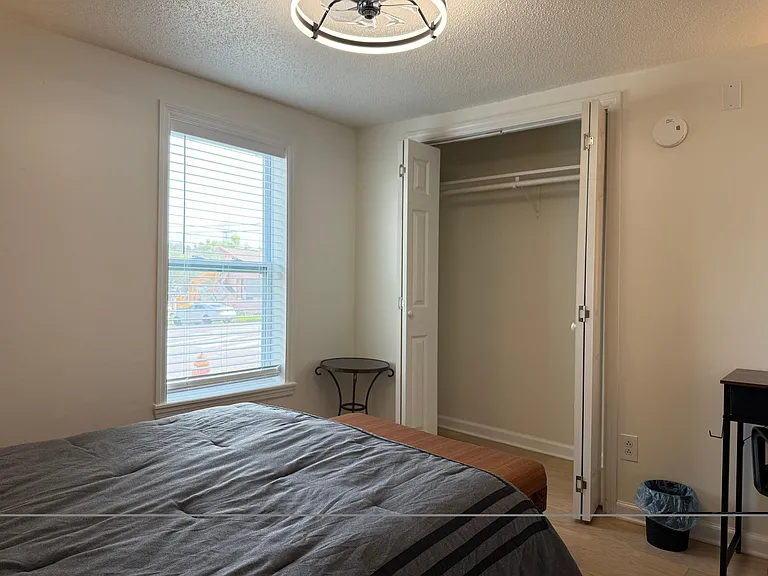 Private bedroom featuring a large window with blinds and a roomy closet for convenient storage and easy organization.