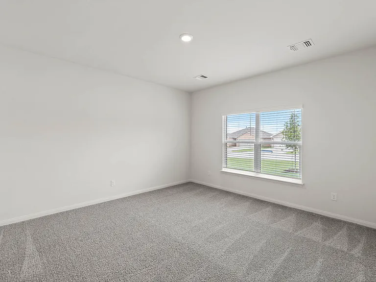 The large master bedroom has a window that lets in natural light and backyard views.