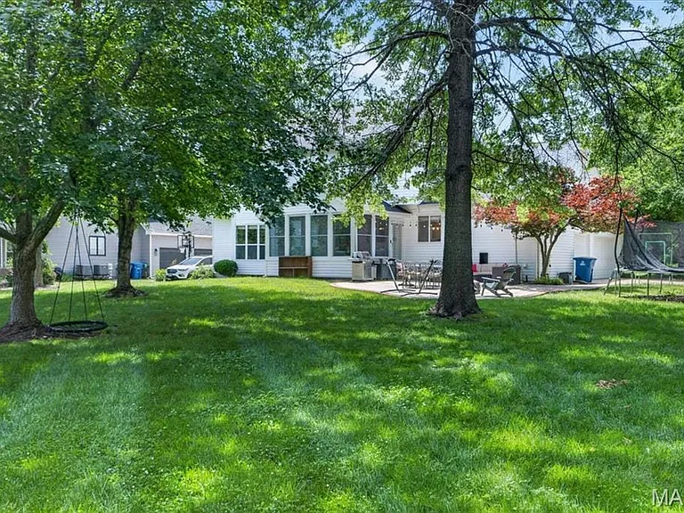 Spacious rear lawn with mature trees and a rear patio