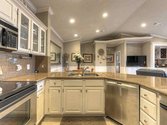 A view from the kitchen to the living area shows recessed lights, tall, vaulted ceilings, and beauti