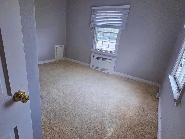 Sunlit bedroom with soft carpet and a peaceful ambiance.