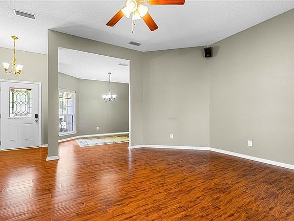 Empty room featuring visible vents, ceiling fan with notable chandelier, baseboards, and wood finished floors