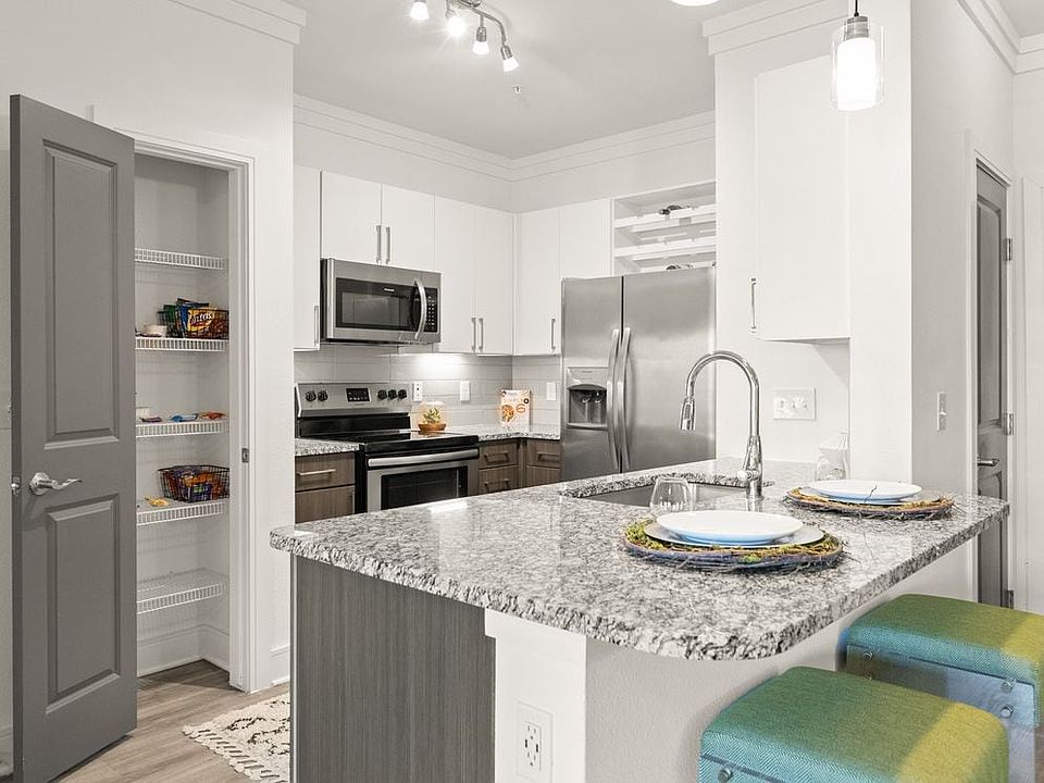 Kitchen with white and espresso cabinetry, speckled granite countertops, stainless steel appliances, and hard surface flooring