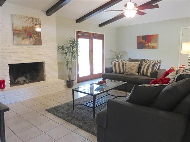 Spacious living area is open to dining and kitchen pass through with vaulted ceilings and wood burning fireplace. French doors open onto oversize patio