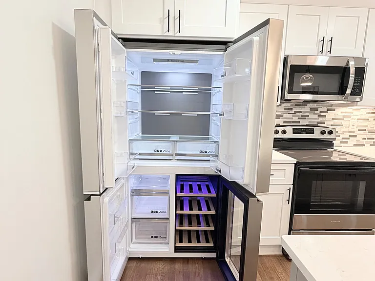 Updated kitchen with stainless steel appliances, ample shaker cabinetry, and a large fridge with wine storage.