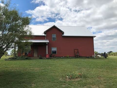 Great room with living, full kitchen and dining. Two bedrooms and one bath downstairs. Stairs leading to loft that overlooks great room. Two bedrooms and one bath upstairs. West side (right) is large garage/barn with tall overhead door.