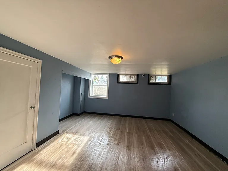 Unit B. Bedroom or living room with closet and 3-windows in half basement level.