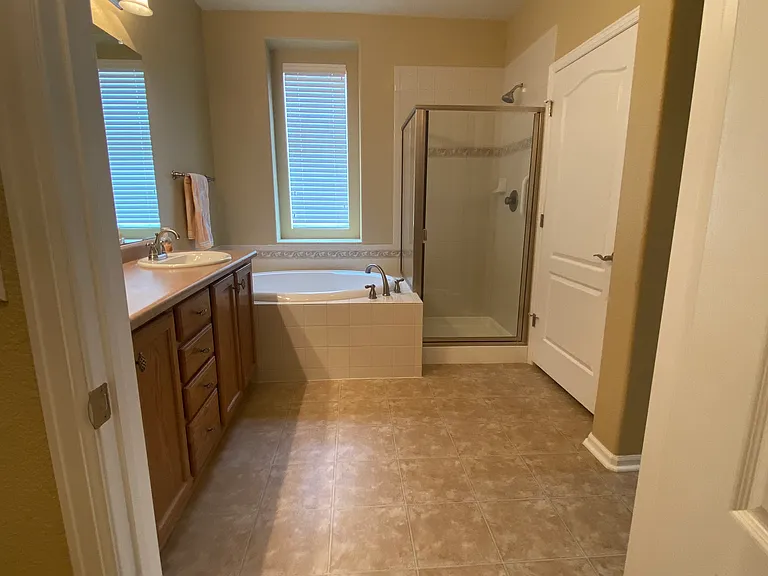 Master bath view from the large walk-in closet. Private commode room is behind the door next to the shower.