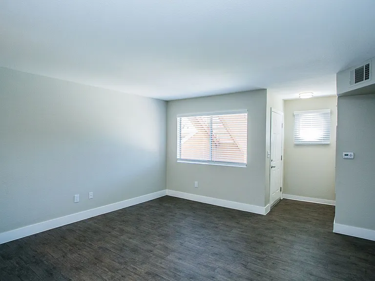 Living area with wood-style flooring, large baseboards, two-tone paint, and window.