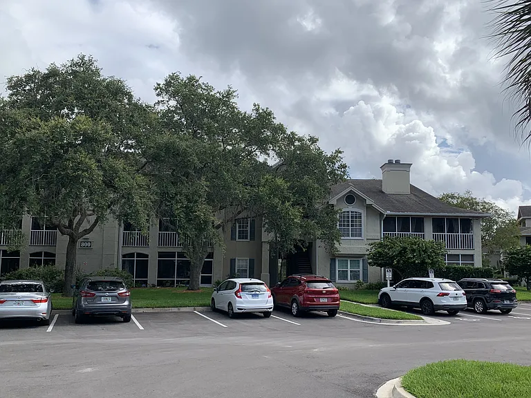 Front of Building 800. Unit 816 is accessed through the shaded walkway above the red car.