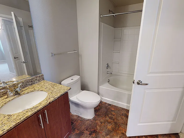 Apartment bathroom with large soaking tub and wood-style flooring.