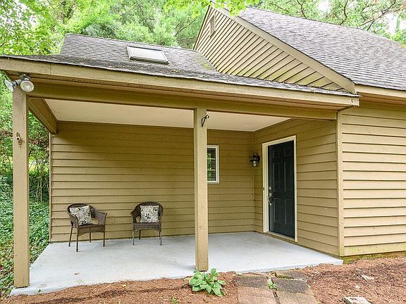 Large lounging front porch. House surrounded by trees for a lovely, secluded feeling.